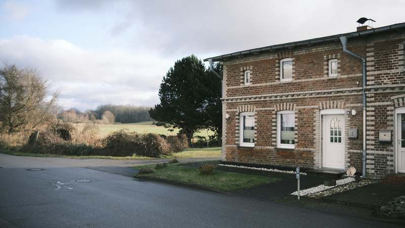 Stone cottage with ivy-covered facade, wooden door, and flower boxes in countryside setting